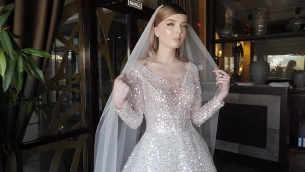 Attractive blonde poses for photo shoot holding long veil — Stockvideo
