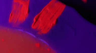 painter draws purple neon lines with black paintbrush macro