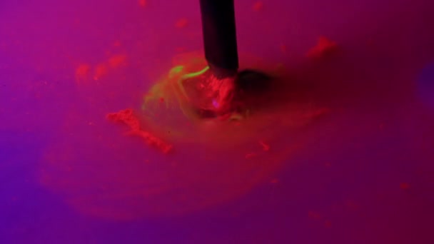 Skilled artist washes black paintbrush from neon farb — Stockvideo