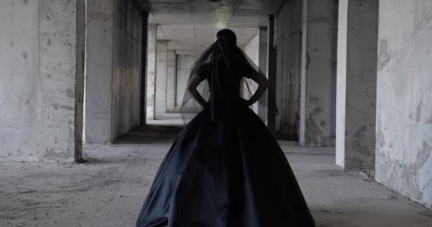 Модель в длинном черном платье ходит по недостроенному строительному залу — стоковое видео