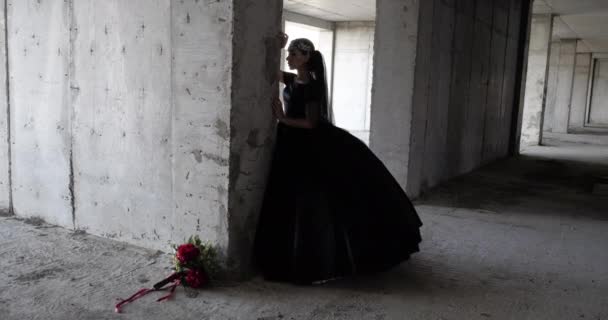 Model v dlouhých černých šatech představuje v blízkosti velkého betonového nosníku — Stock video