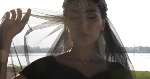 Flicka i diamant tiara och svart slöja poserar på baksidan solljus — Stockvideo