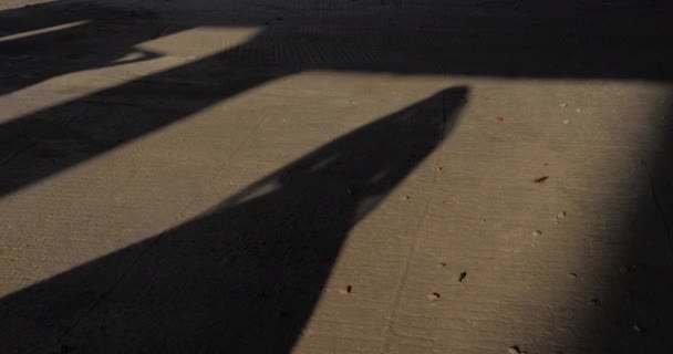 Wanita langsing dalam bayangan gaun panjang berjalan sepanjang aspal abu-abu — Stok Video