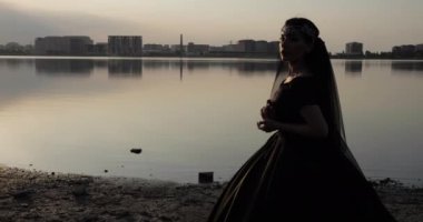Atlı kadın resimli şehir manzarasına karşı sahilde duruyor.