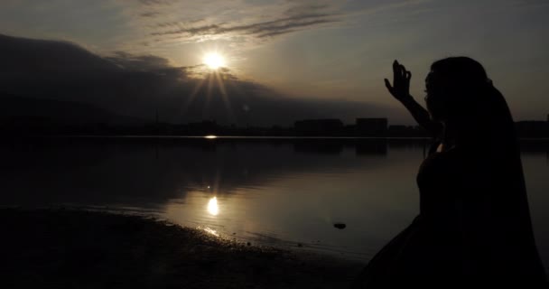 Αλογογυναίκα σε σιλουέτα φόρεμα κινείται χέρι κοιτάζοντας το ηλιοβασίλεμα — Αρχείο Βίντεο
