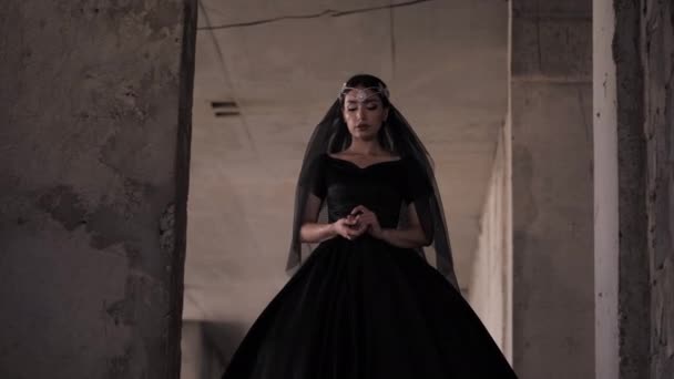 Jonge vrouw in lange zwarte jurk met sluier en tiara wandelingen — Stockvideo