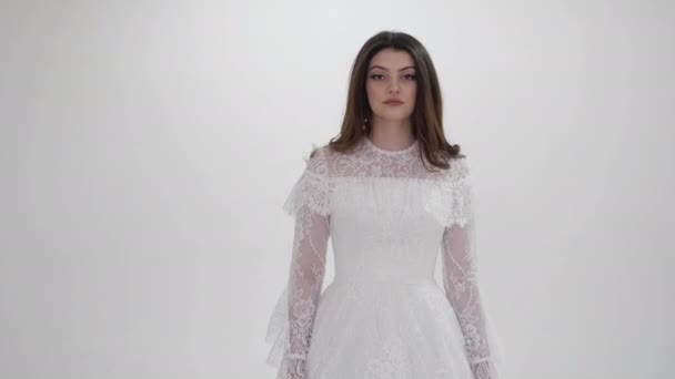 Jeune femme en robe blanche à manches dentelles pose en studio — Video