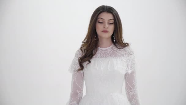 Elegant bride with loose curly hair poses in light studio — Stock video