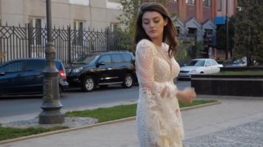 Dantelli elbiseli çekici esmer, geniş kollu, arabaların yanında.