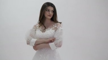 Beyaz gelinlik içindeki zarif gelin kameraya poz veriyor.