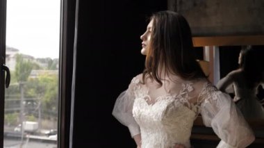 Dantelli yakalı esmer, odanın penceresinden dışarı bakıyor.