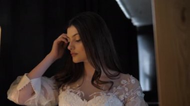 Dantelli elbiseli profesyonel model uzun kıvırcık saçları düzeltiyor.