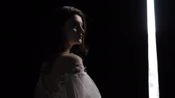 Брюнетка в открытом плече свадебное платье возле темных занавесок — стоковое видео