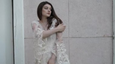 Beyaz dantelli elbise giyen profesyonel bir model uzun, dağınık saçları düzeltiyor.