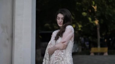 Gelinlikli kız sokakta dikiliyor ve dik duruyor.