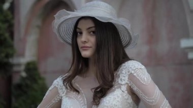 Beyaz şapkalı profesyonel model kameraya poz veriyor.