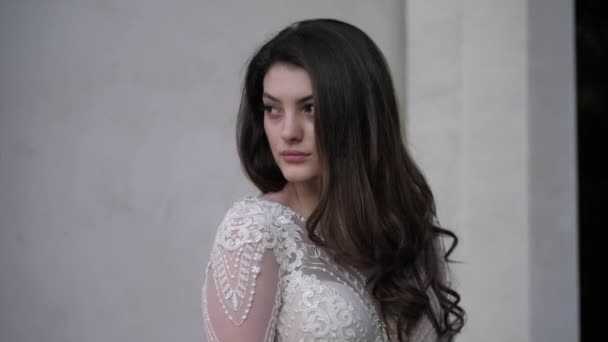 Long haired brunette in lacy dress looks around and poses — Stock Video