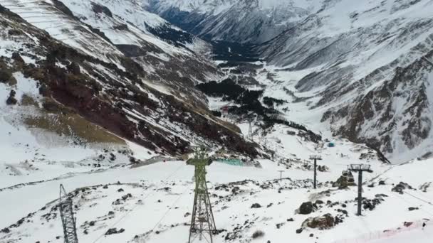 Linhas de energia estão perto de cabo contra montanhas nevadas — Vídeo de Stock