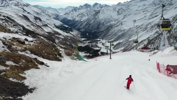 Karlı dağ oteli. Kayakçılar yamaçlarda hızla ilerliyor. — Stok video