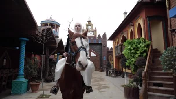 穿着阿拉伯服装的女孩骑着马沿着餐馆院子走 — 图库视频影像