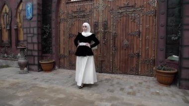 Shayla 'lı geleneksel elbiseli kız bahçede yürüyor.