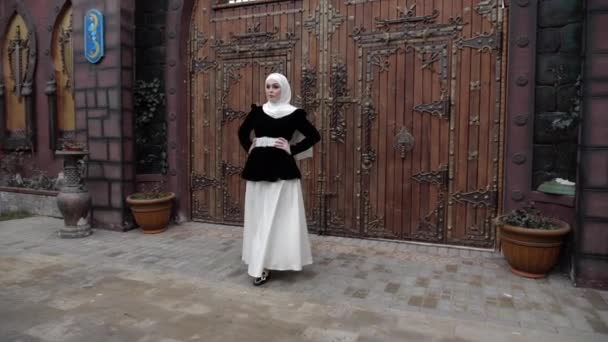 Девушка в традиционной одежде с Шейлой гуляет по двору — стоковое видео