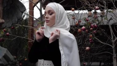 Beyaz tesettürlü, Arapça elbiseli bir kadın ve çıplak ağacın yanında beyaz bir tesettür