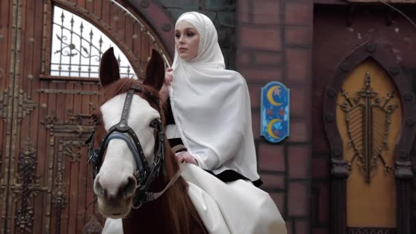 Omtänksam dam i hijab sitter på häst i dekorerad gård — Stockvideo