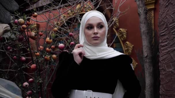 Senhora em hijab com pérolas poses perto de árvore nua decorativa — Vídeo de Stock