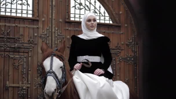 Girl in traditional Arabian costume sits on chestnut horse — Stock Video