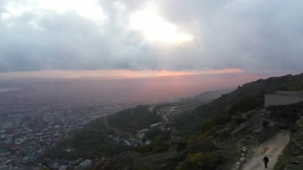 Mann läuft auf Canyonpfad gegen Stadt- und Abendhimmel — Stockvideo