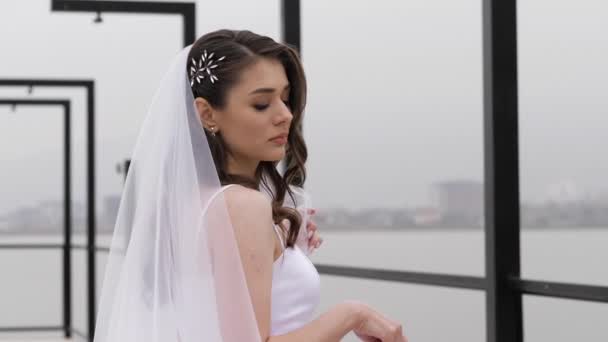 Elegante giovane donna in abito da sposa stretto con soffice velo — Video Stock