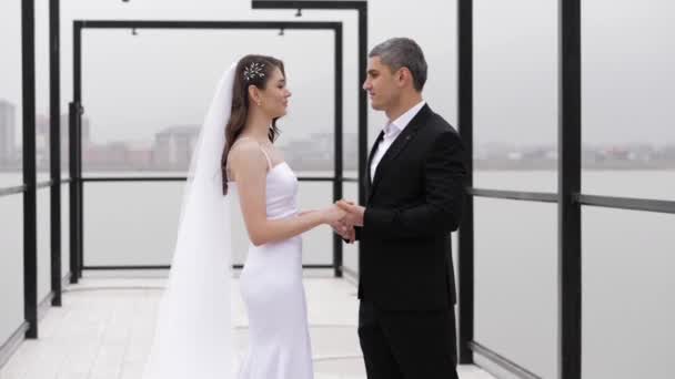 Elegante fidanzato tiene sposa sottile con le mani soffice velo — Video Stock