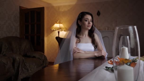Μακρυμάλλη νύφη με λυπημένο πρόσωπο κάθεται στο τραπέζι με κεριά — Αρχείο Βίντεο