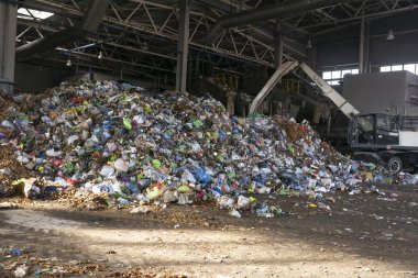 Grodno, Belarus - 26 Ekim 2019: Kazıcı atık geri dönüşüm fabrikasındaki çöpleri ayırıyor.