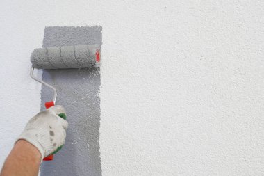 Elinde boya rulosuyla, duvarları boyuyor.