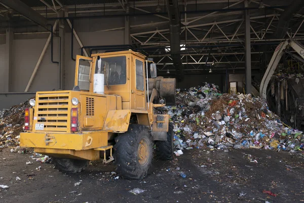 Grodno, Belarus - 26 Ekim 2019: Kazıcı atık geri dönüşüm fabrikasındaki çöpleri ayırıyor.