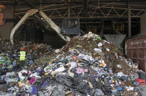 Grodno, Belarus - 26 Ekim 2019: Kazıcı atık geri dönüşüm fabrikasındaki çöpleri ayırıyor.