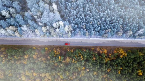 Hranice podzimu a zimy. Auta na silnici v lese shora pohled z dronu. — Stock fotografie