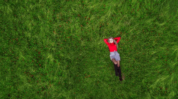 Dívka ležící na zeleném trávníku nad hlavou pohled s drone — Stock fotografie