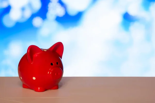 red piggy Bank on the table on a blue background