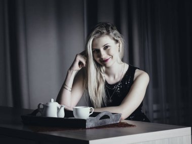 Yemek masasında şık sarışın bir kızın portresi.