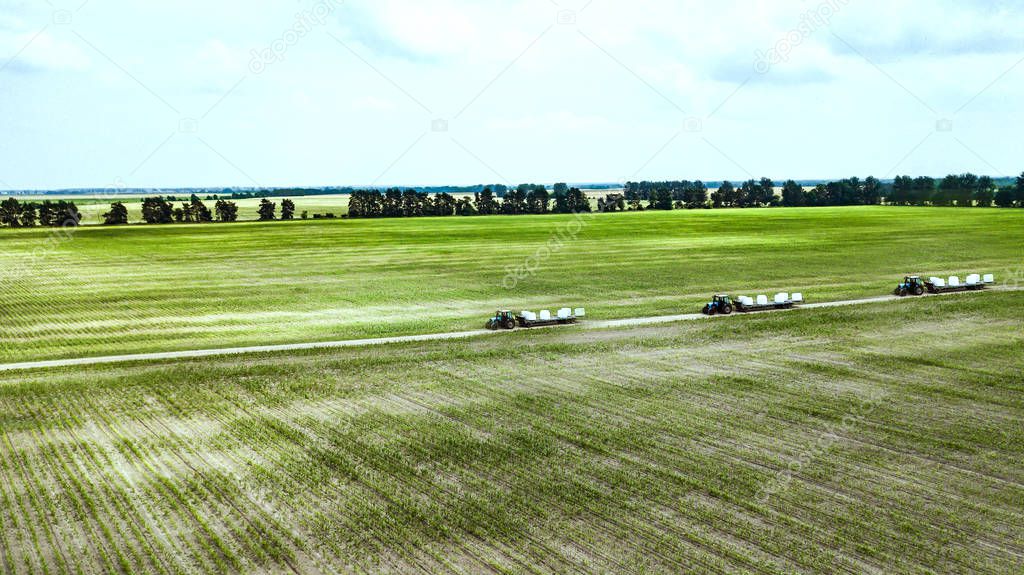 tractors carry bales of straw on the field top view