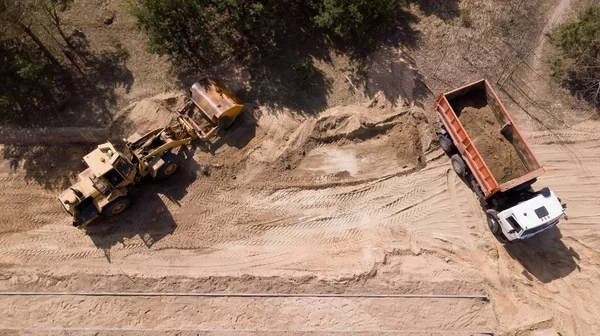 The loader loads the sand into the truck. Repair of roads. the view from the top — ストック写真