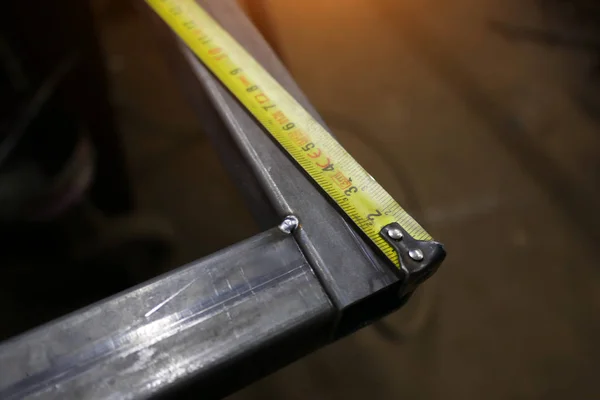Esquina de metal y cinta métrica en un banco de trabajo —  Fotos de Stock