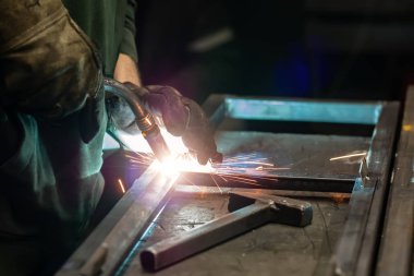 Kaynakçı çerçeveyi pişirir. Kaynakçı metali pişirir. Kaynakçı metal yapılar pişiriyor. Kaynak işe yarıyor. Kıvılcımlar, erimiş metal