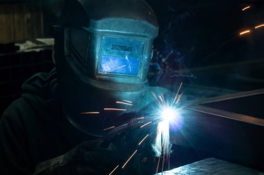 Kaynakçı çerçeveyi pişirir. Kaynakçı metali pişirir. Kaynakçı metal yapılar pişiriyor. Kaynak işe yarıyor. Kıvılcımlar, erimiş metal