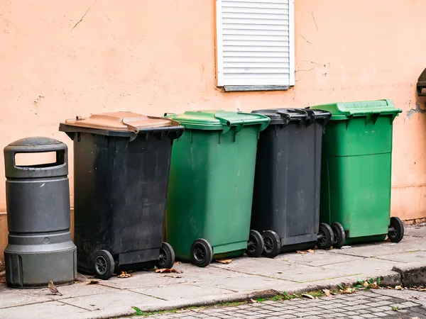 Duvarın yanında birkaç çöp tenekesi duruyor.