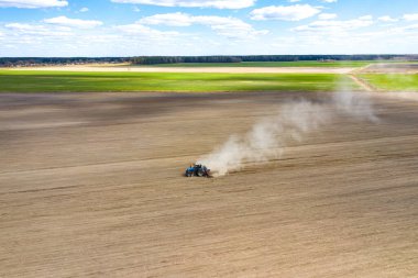 Atlı ekiciyle traktörün hava görüntüsü tarlaya ekin ekiyor. Çiftçi ekme işlemi için tarım makineleri kullanıyor, üst görünüm