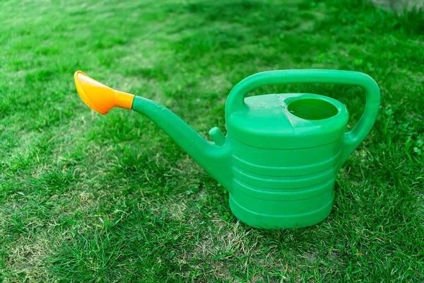 green watering can on the lawn